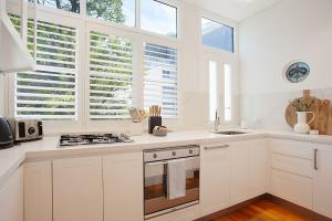 uma cozinha branca com armários brancos e janelas em Chelsea Chic Paddington em Sydney