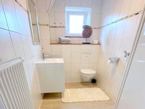 a bathroom with a sink and a toilet and a window at Ferienwohnung Emilia in Garding