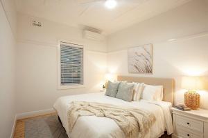 a white bedroom with a bed and a window at Coogee Rest in Sydney