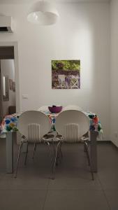 mesa de comedor con 2 sillas y una pintura en Iris, en Marina di Ragusa