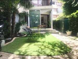 een tuin met een tafel en stoelen op het gras bij EXIGEHOME - Bel appartement à 500 m des JOs équitation - Piscine et tennis in Le Chesnay