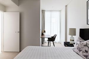 a white bedroom with a bed and a desk at Cosmopolitan Heights in Sydney