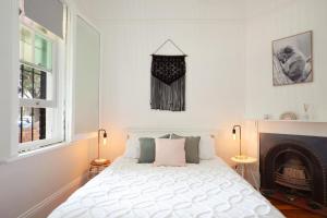 a bedroom with a white bed and a fireplace at Garden Oasis Sydenham in Sydney