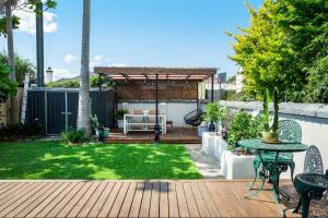 a backyard with a wooden deck with a table and chairs at Garden Oasis Sydenham in Sydney