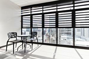 a table and two chairs in a room with a large window at Cosmopolitan Heights in Sydney