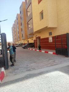 dos hombres están parados fuera de un edificio en EL SARAYA M'SILA DZ, en MʼSila