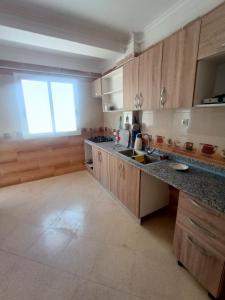 eine Küche mit Holzschränken, einem Waschbecken und einem Fenster in der Unterkunft EL SARAYA M'SILA DZ in MʼSila