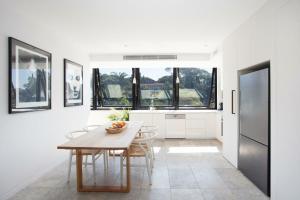 een witte keuken met een houten tafel en stoelen bij The Treehouse Penthouse in Sydney