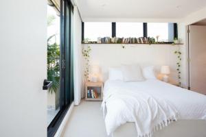 a bedroom with a white bed and a window at The Treehouse Penthouse in Sydney