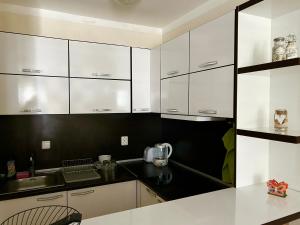 a white kitchen with black walls and white cabinets at Utopia Apartments Primorsko in Primorsko