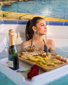 uma mulher numa banheira com uma bandeja de comida e uma garrafa de vinho em Villa l'Infinito em San Felice Circeo