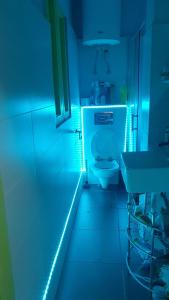 Un baño con un inodoro blanco en una luz azul. en Great Buda Apartman, en Budapest 9 fotos más