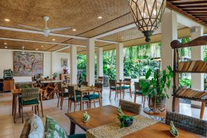 un ristorante con tavoli, sedie e soffitto di Jati Cottage ad Ubud