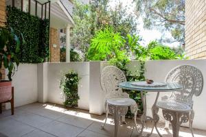 un patio con mesa, sillas y una valla en La Brisa Coogee en Sídney