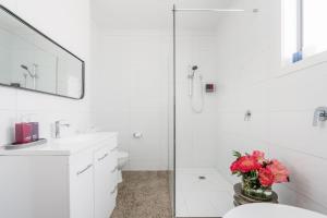 a white bathroom with a toilet and a vase of flowers at Embracing Evandale in Evandale