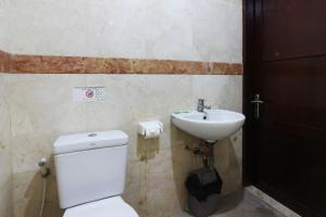 bagno con servizi igienici bianchi e lavandino di Jambrut Inn a Giacarta