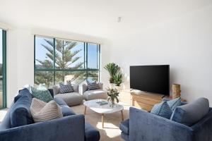 a living room with blue couches and a flat screen tv at Palm Breeze in Coogee in Sydney
