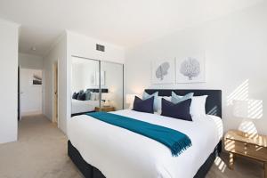 a bedroom with a large white bed with blue pillows at Palm Breeze in Coogee in Sydney
