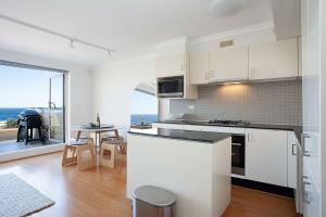 uma cozinha com armários brancos e vista para o oceano em Ocean view Clovelly em Sydney