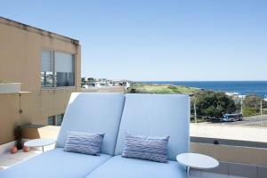 a blue couch on a balcony with a view of the ocean at Ocean view Clovelly in Sydney