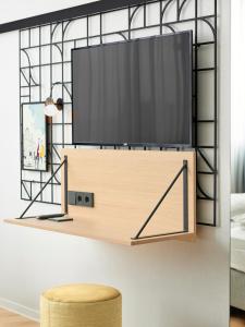 a television on a shelf in a living room with a stool at H2 Hotel Wien Schönbrunn in Vienna