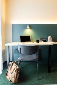 a desk with a laptop and a chair with a bag at Green Park Hotel Brugge in Bruges