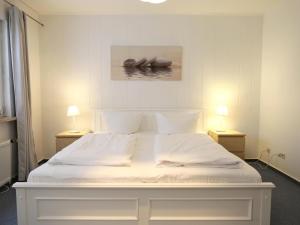 uma cama branca num quarto com 2 candeeiros em Fernsicht-12b-EG em Wenningstedt