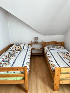 two twin beds in a room with wooden floors at APARTMENT ON THE ROAD S-61 in Szypliszki