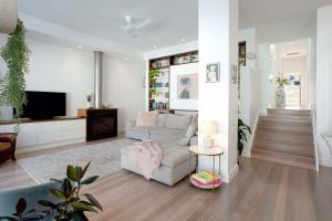 a living room with a couch and a tv at The Cali Beach house Bronte in Sydney