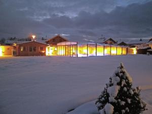 a building with lights in the snow at night at Alluring Holiday Home in Ubersee with Whirlpool in Übersee