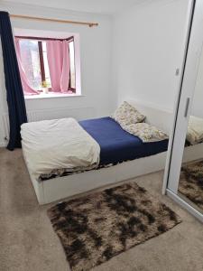 Schlafzimmer mit einem Bett mit einem Spiegel und einem Fenster in der Unterkunft Spacious flat with free parking in Croydon in Croydon