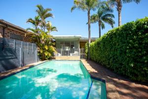 a swimming pool in front of a house with palm trees at Palm Springs in Collaroy in Collaroy