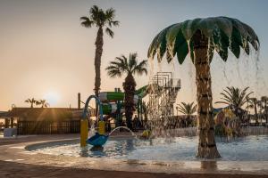 um parque aquático com um escorrega e uma palmeira em ALEGRIA Colonial Mar em Roquetas de Mar