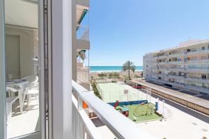 uma varanda com vista para um campo de ténis e para o oceano em Global Properties, Las dachas 1 - Apartamento en primera línea de playa em Canet d'En Berenguer