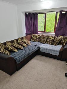 ein Sofa mit Kissen darauf im Zimmer in der Unterkunft Spacious flat with free parking in Croydon in Croydon