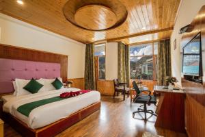 a bedroom with a large bed and a desk and chairs at Sarthak Regency by M K Hospitality,Rangri, Manali,HP,Just 1 kms from Volvo parking in Manāli