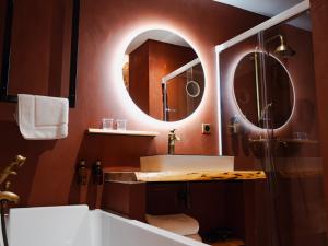 ein Badezimmer mit einer Badewanne, einem Waschbecken und einem Spiegel in der Unterkunft Hôtel Château Héloïse 