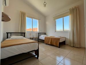een slaapkamer met 2 bedden en 2 ramen bij Coral Bay Sunbeam Villa in Coral Bay