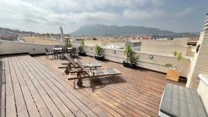 eine Holzterrasse mit Tischen und Stühlen auf dem Dach in der Unterkunft Apartamentos Elegance El Conserje in Denia