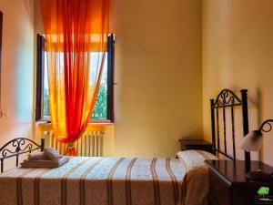 1 dormitorio con 1 cama y una ventana con cortinas de color naranja en La Staccionata, en Arpino