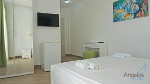 una camera da letto con un letto bianco e asciugamani di Angelina Hotel a Ormos Panagias