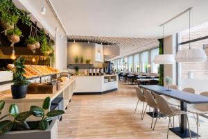 un restaurante con mesas, sillas y plantas en Green Park Hotel Brugge en Bruges