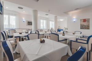 a dining room with white tables and blue chairs at CENTRO HOTEL in Marcon