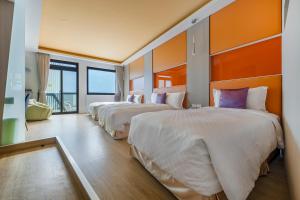 - 2 lits dans une chambre d'hôtel aux murs orange dans l'établissement Pacific Inn, à Kenting