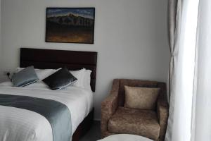 a bedroom with a bed and a chair at Epitome Apartment, Swara Ranch-Nanyuki in Nanyuki