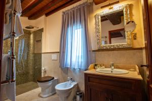 a bathroom with a sink and a toilet and a mirror at Torciano Hotel Vecchio Asilo in San Gimignano