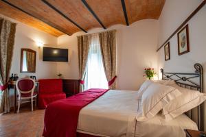 a bedroom with a large bed and a red chair at Torciano Hotel Vecchio Asilo in San Gimignano