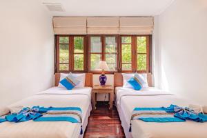 two beds in a room with two windows at Kamala Beach Estate Resort - SHA Extra Plus in Kamala Beach +174 photos