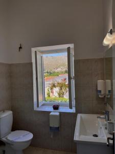 a bathroom with a toilet and a sink and a window at Alinda Hotel in Alinda