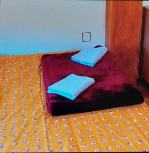 a bed with two blue pillows on top of it at Vikendica Raj u prirodi in Prijedor